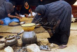 Image du Maroc Professionnelle de  Sous une tente bédouine plusieurs femmes du Sahara  préparent le couscous durant le grand Moussem de Tan Tan, classé en 2005 patrimoine immatériel humain mondial de l'Unesco. Le Moussem est une sorte de foire annuelle, à la fois économique, culturelle et sociale. Chaque année la majorité des tribus et des grandes familles nomades du désert se retrouvent sur un site désertique "Place de la Tolérance et de la Paix " à la périphérie de Tan Tan où  danse, chants, course de chameaux et fantasia font partie des festivités. , Samedi 18 septembre 2004, ((Photo / Abdeljalil Bounhar) 